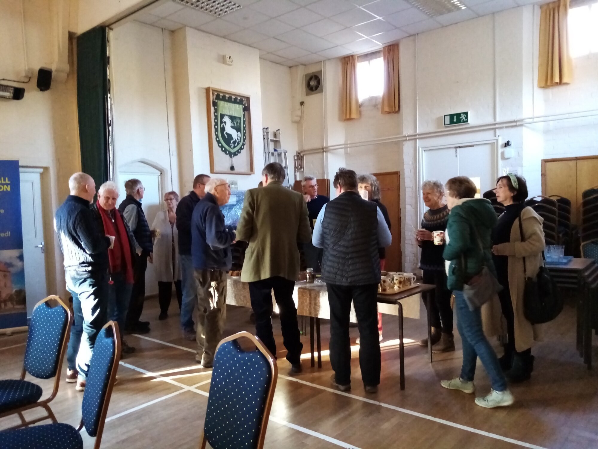 People socialising around tea and coffee in a village hall